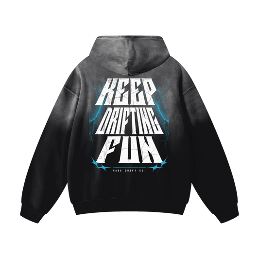 A black and gray gradient hoodie shown from the back, featuring a large graphic print with the words 'KEEP DRIFTING FUN' in white and blue lightning accents. The brand 'DRIFT DRIFT CO.